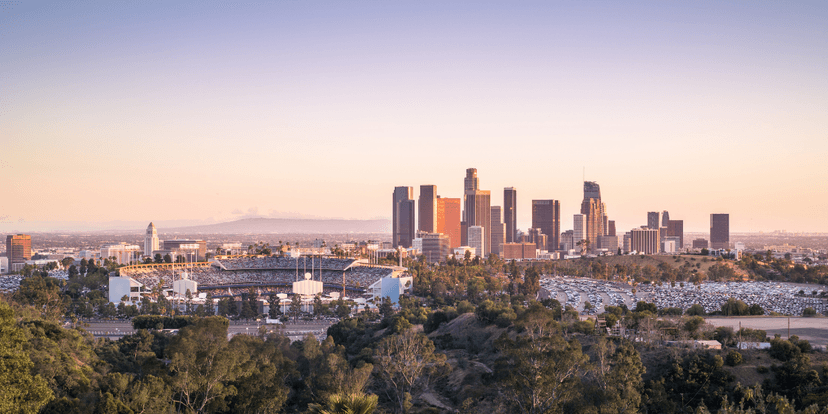 Skyline of Los Angeles at sunset with stadium and parking lot in foreground