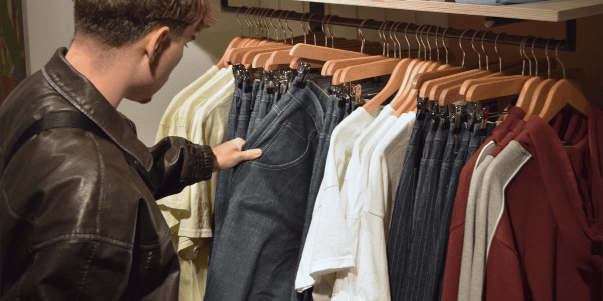 Person selecting jeans from a clothing rack in a store display