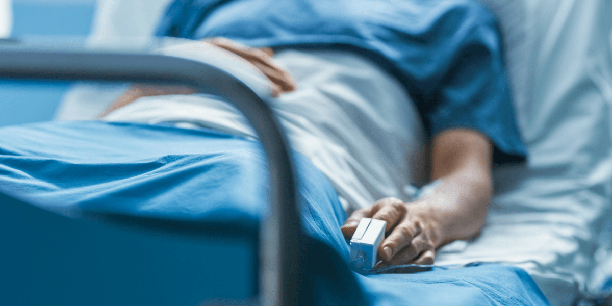 Patient lying in a hospital bed with a pulse oximeter on their finger