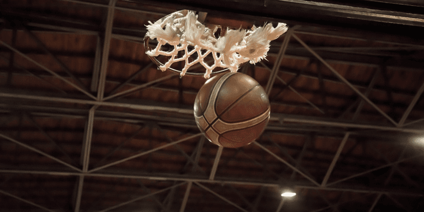 A basketball is about to go through a basketball hoop in a gymnasium