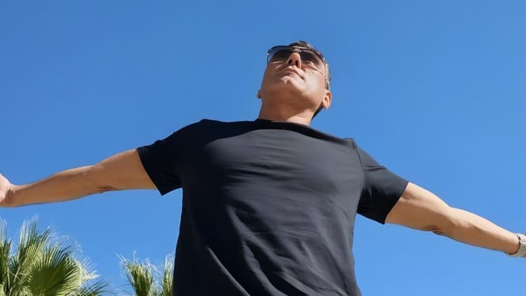 Dylan Garcia embraces the moment outdoors, radiating positive energy with his arms wide open under a clear blue sky.