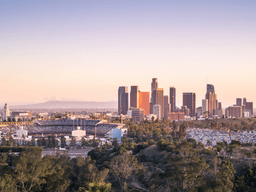 Skyline of Los Angeles at sunset with stadium and parking lot in foreground