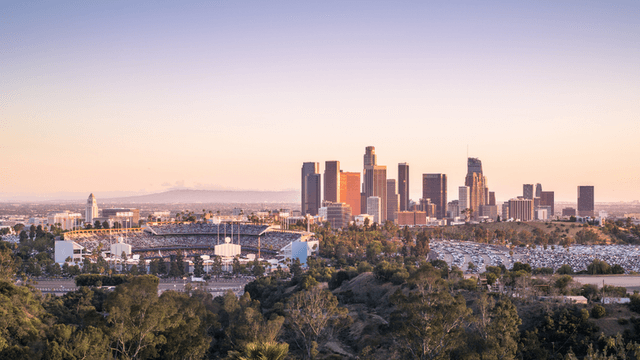 Skyline of Los Angeles at sunset with stadium and parking lot in foreground