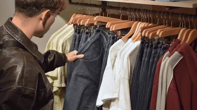 Person selecting jeans from a clothing rack in a store display