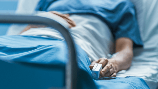 Patient lying in a hospital bed with a pulse oximeter on their finger