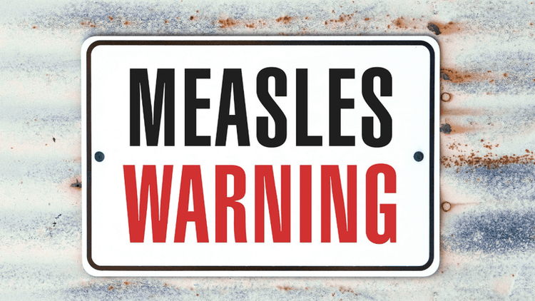 Sign displaying "MEASLES WARNING" in bold black and red letters on a weathered background
