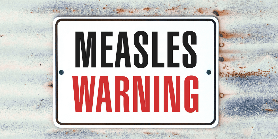 Sign displaying "MEASLES WARNING" in bold black and red letters on a weathered background