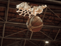 A basketball is about to go through a basketball hoop in a gymnasium
