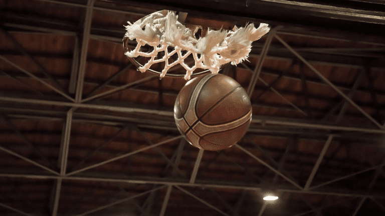 A basketball is about to go through a basketball hoop in a gymnasium