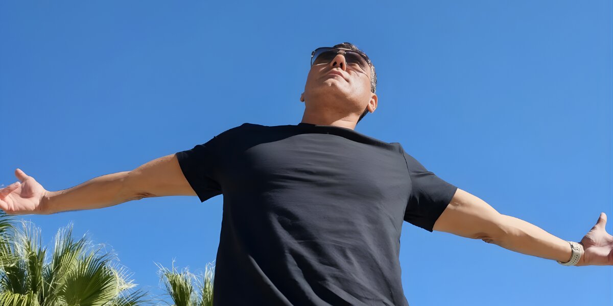 Dylan Garcia embraces the moment outdoors, radiating positive energy with his arms wide open under a clear blue sky.